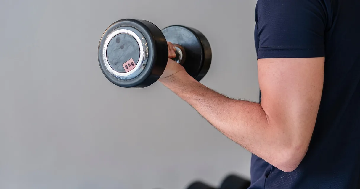 Homem levantando halter em exercício de ombro