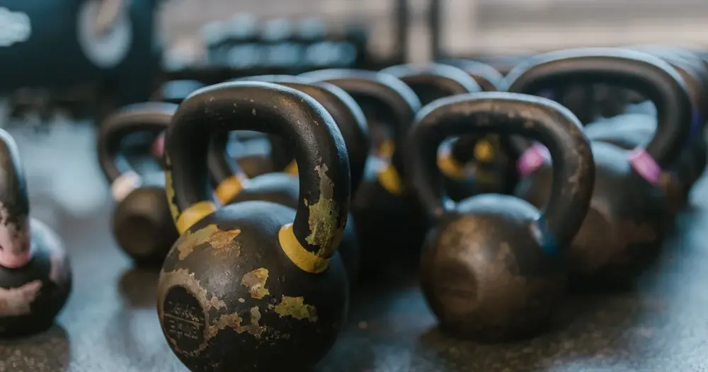 Kettlebells pretos enfileirados no piso de uma academia, sem pessoas, ilustrando sites para achar personal trainer em Rio Verde